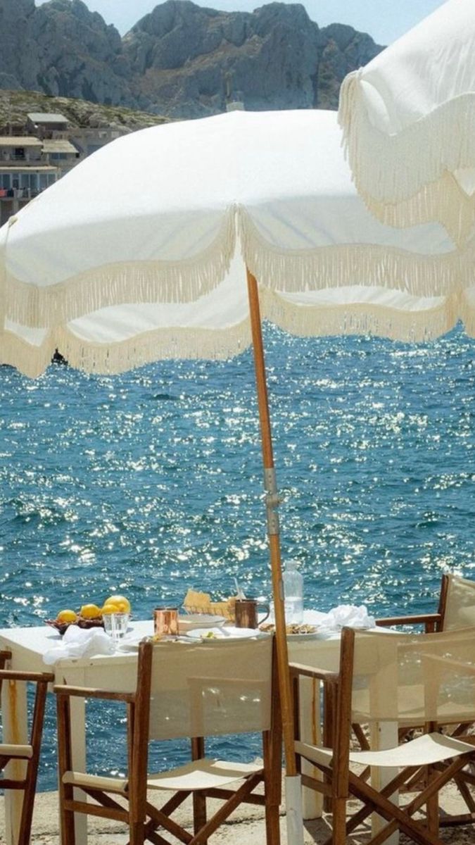Seafront dining table overlooking the Aegean Sea in Mykonos with luxury beach umbrellas and coastal views